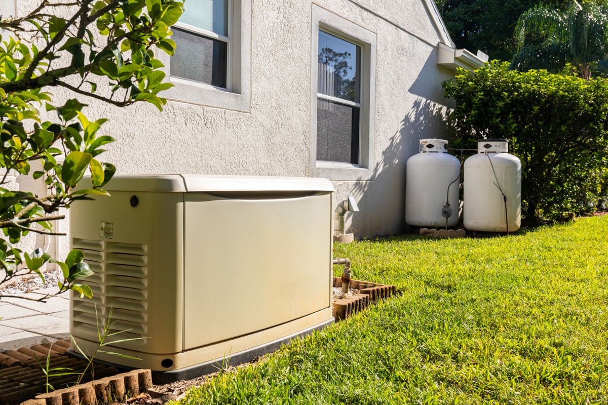 Generator and propane tanks beside house ready for propane cylinder requalification