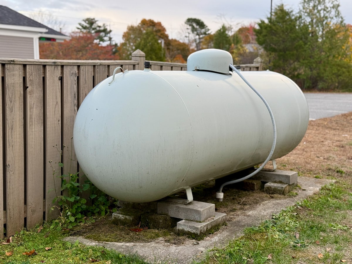Large propane tank beside wooden fence