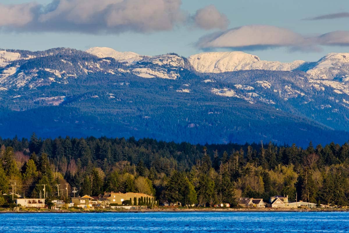 Snowy mountains above a tranquil coastline.